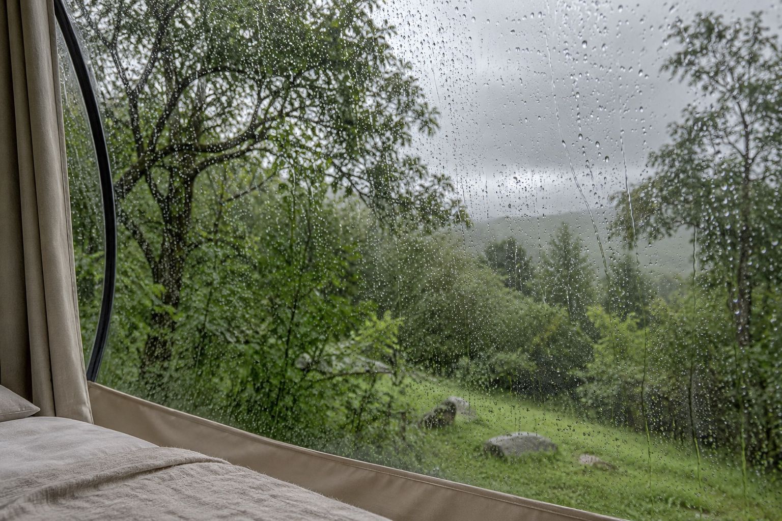 Ilustración generada con IA de gotas de lluvia sobre una cubierta transparente con árboles al fondo